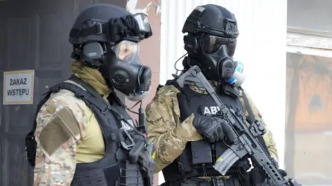 ABW Two men wear gas masks and military uniform and carry guns