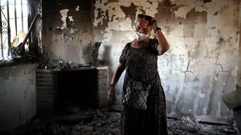 AFP via Getty Images Concepcion Garcia enters her home for the first time after it was destroyed by a raging wildfire that swept through areas of the town of Navas del Rey, 55 kilometers southwest of Madrid, on July 29, 2026