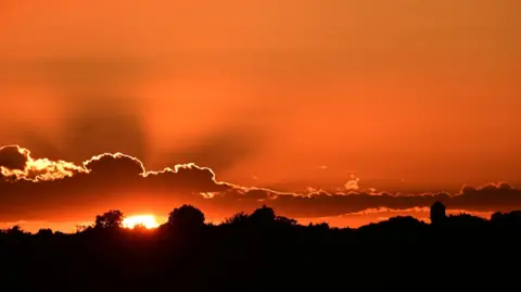 Getty Images Dramatic and vibrant orange sunset sky with silhouetted landscape and sun rays breaking through clouds, in London, the UK