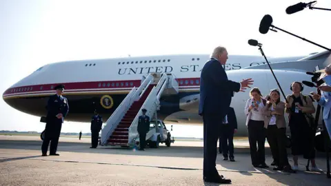 Getty Images Trump stands in front of Qatari-gifted Air Force One and speaks to reporters who are holding boom microphones