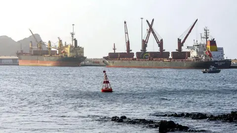 AFP via Getty Images Large cargo ships standing still in ocean water