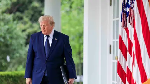 Getty Images Donald Trump walking near an American flag at the White House. 