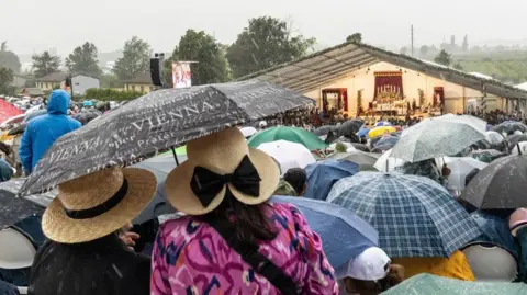 EPA Worshippers stand under umbrellas amidst heavy rain during the episcopal consecration of Catholic priests as part of a pontifical Mass organized by the Society of Saint Pius X in Econe, near Sion, Switzerland, 1 July