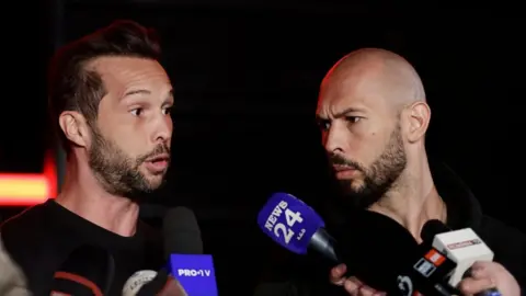 EPA Tristan (left) and Andrew Tate speaking to members of the media in March 2025.