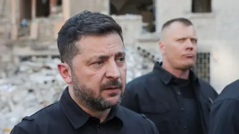 Getty Images President of Ukraine Volodymyr Zelensky speaks to the press as he visits an apartment block in the Darnytskyi district severely damaged by a massive Russian missile attack