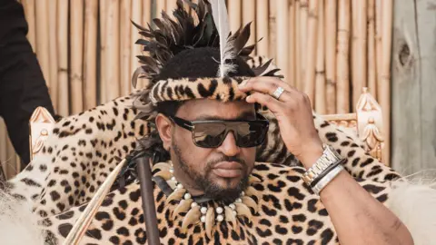 AFP via Getty Images King Misuzulu kaZwelithini is pictured in sunglasses and leopard print ceremonial clothing