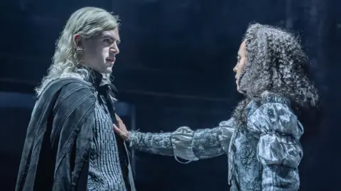 Johan Persson Noah Ritter (Prince Rhaegar Targaryen) and Harmony Rose-Bremner (Lyanna Stark) facing each other in costume in a scene from Game of Thrones: The Mad King. She has an arm outstretched with her palm on his chest