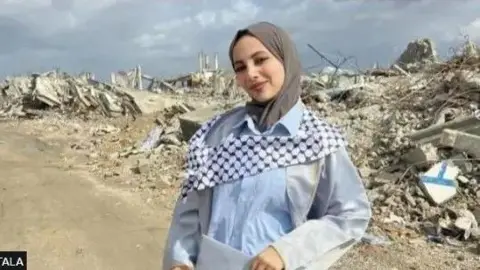 TALA A girl in Gaza stands before a background of rubble