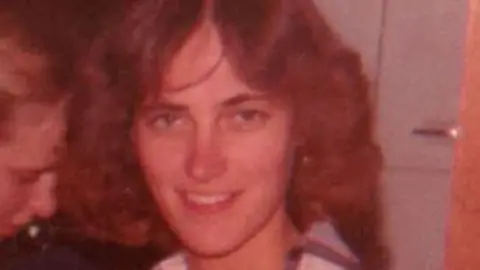 Elgin Police Department Karen Schepers smiles at the camera, her brown wavy hair split in the middle in a typical early-1980s style 