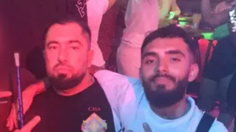 Swedish Police Two bearded men sitting in what appears to be a nightclub with people dancing behind them