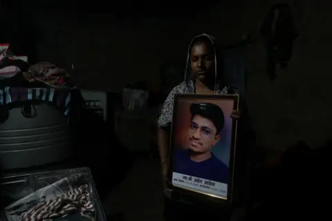 Reuters Babita Kumari, sister of Pradeep Kumar, 22, an aspirant doctor who took his own life after the results of the first NEET exam were cancelled, poses for a picture as she holds a photo of her brother at her home in Jhunjhunu, India, July 21, 2026. REUTERS/Francis Mascarenhas
