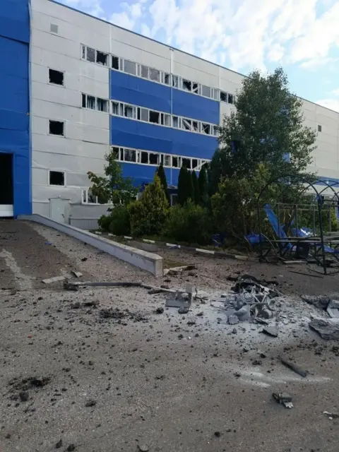 Handout The windows of a large industrial building are smashed, with the tarmac in front charred and damaged. Debris is littered on the ground.