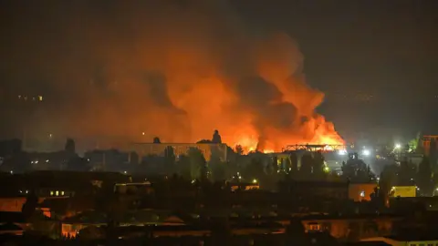 Getty Images A fire breaks out following massive Russian ballistic missile strikes in the Ukrainian capital of Kyiv, with orange and black plumes of smoke expanding across the night sky.