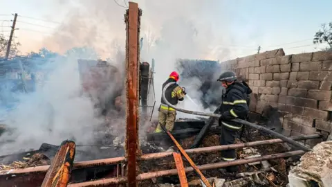 DSNS Ukraine Firefighters tackle a blaze in a destroyed house after a Russian drone attack on Balakliya, north-eastern Ukraine. Photo: 6 August 2026
