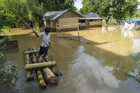 Anadolu via Getty Images A boy uses a makeshift banana raft to navigate floodwaters past submerged homes in a flood-affected neighborhood, on July 22, 2026 in Jorhat, India. 