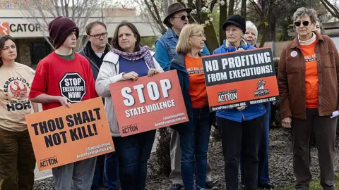 Getty Images A group of protesters in coats and hats hold signs that say "stop state violence" and "thou shalt not kill".