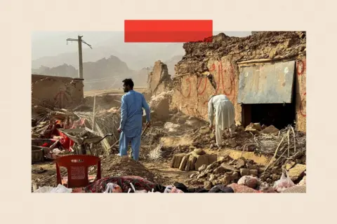 Reuters A man in a blue tunic and trousers surveys the damage caused by an earthquake. He stands amid the rubble of a home, looking towards mountains in the distance. Another figure on the right bends over