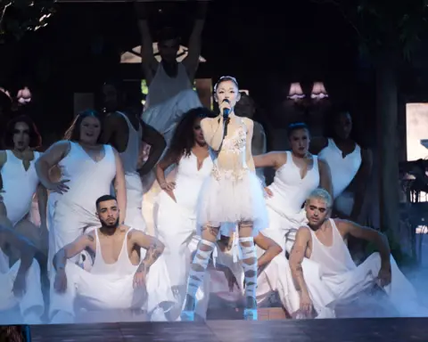 Katia Temkin Ariana Grande  at the Oakland Arena on June 6 in California. She is dressed in a white lace dress, surrounded by dancers in plain white costumes
