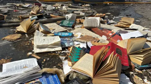 Books strewn across the ground all damaged and burnt