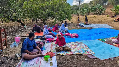 Getty Images A group of people sit outdoors on blankets and tarps