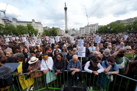 PA Media A crowd of people gather in Trafalgar Square as part of a vigil for Jason Arday. Some of them are holding placards.