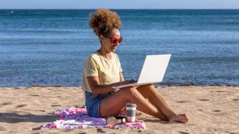 Getty Images A woman with her laptop on the beach