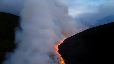 RSPB Scotland A drone image showing a bright zig-zag line of fire on a hillside at night. Thick smoke rises from the flames.