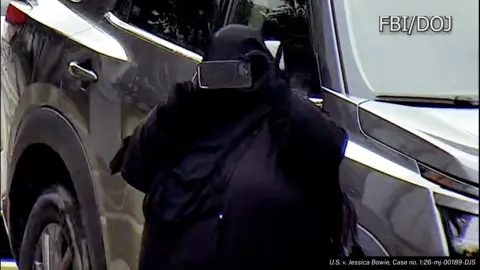 DOJ/FBI The woman in all black taking a photo