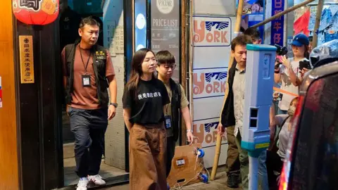 Getty An employee is escorted away from Have a Nice Stay independent bookstore by Hong Kong national security police. 