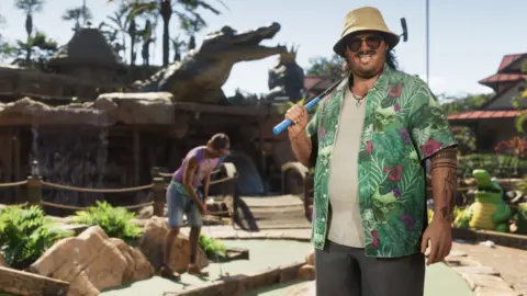 Rockstar Games Cal Hampton, a character from GTA 6, stands in front of an alligator-themed crazy golf course. He holds a putter over one shoulder, and pulls a tongue-out face at the viewer. His loud, green, floral shirt stands out against the browns of the golf course. Behind him, a companion can be seen lining up an attempted putt, while a large alligator statue looms over the course.