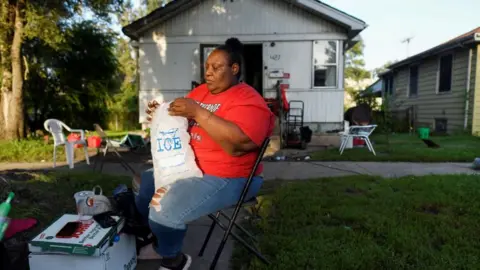 Reuters Dinky Austin gets ice to cool off with ice water, as thousands of residents remain without electricity more than a week after severe storms struck Gary, Indiana