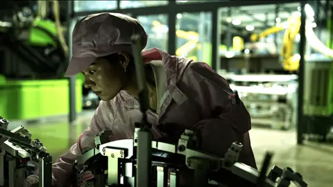 A young female worker examining a machine at the Leapmotor factory.