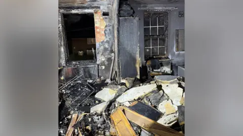 London Fire Brigade Jahmell Campbell's flat after his e-bike caught fire. The walls have been scorched and huge chunks of the ceiling have been blown apart and can be seen sitting on the floor. 