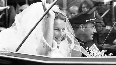 AFP via Getty Images A picture taken on August 29, 1968 shows Norway's Crown Prince Harald and Sonja Haraldsen waving as they leave in their car the Oslo Cathedral during their wedding ceremony. 
