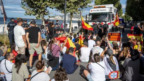 Getty Images Demonstrators block a road where Red Cross volunteers are trying to gain access to distribute food parcels to migrants on Trampolin beach, Ceuta on Thursday.