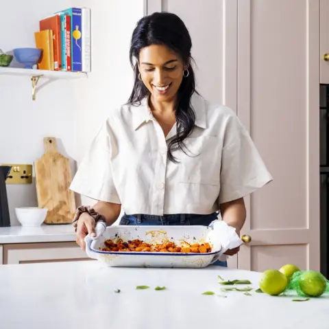 Crystelle Pereira Cook and former Great British Bake Off star Crystelle Pereira stands in a kitchen, looking down at a baking tray