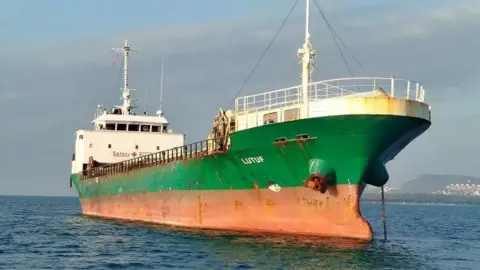 VesselFinder The MV Lutuf anchored close to the shore. The green and orange hull can be seen above the water. 