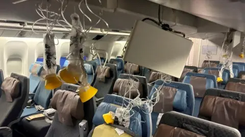 Reuters Oxygen masks hang from the ceiling inside an aircraft cabin. Rows of seats sit empty beneath them.