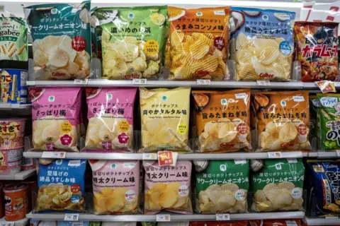 Yuichi Yamazaki/AFP via Getty Images Shelves in a supermarket show packets of crisps in different colours
