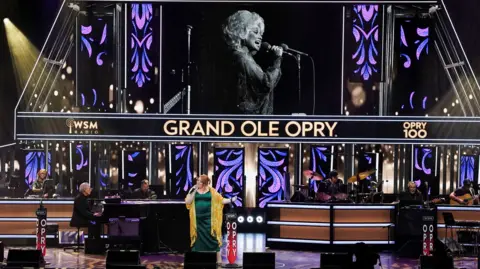 Reuters Jada Star on stage in front of the screen showing a photo of Dolly Parton