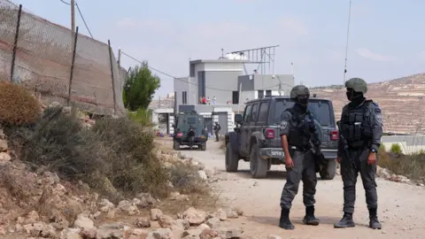 Reuters Members of the Israeli security forces stand guard near a Palestinian house, which was besieged by Israeli settlers, in Qusra