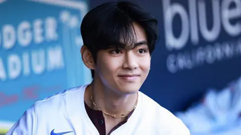 MLB Photos via Getty Images V smiles as he looks at a distance, wearing a baseball shirt