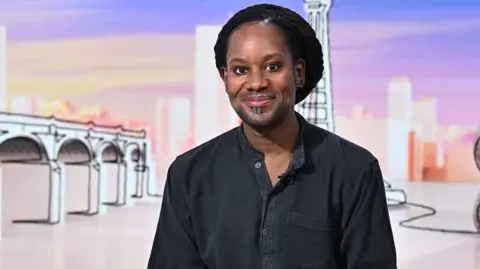 BBC Jason Arday wears a black shirt and smiles at the camera as he appears as a guest on the panel of BBC show Sunday with Laura Kuenssberg