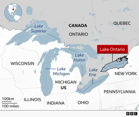 Map of the Great Lakes region of North America showing Lake Ontario highlighted in red. The map labels Ontario and Quebec in Canada and U.S. states including New York, Pennsylvania, Ohio, Michigan, Indiana, Illinois, and Wisconsin. The other Great Lakes, Lake Superior, Lake Michigan, Lake Huron, and Lake Erie, are also labelled