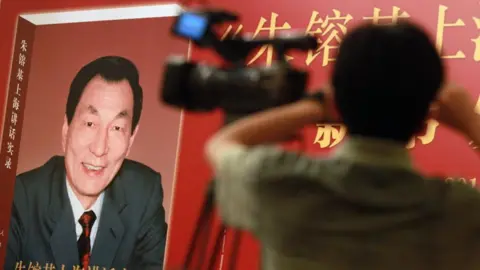 Getty Images Poster of book with former Chinese premier Zhu Rongji on the cover and a blurred image of a man and a TV camera in the foreground