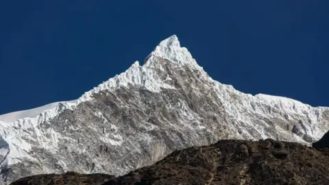 Getty Images A panomanic view of the Langtang Lirung peak. The snowy summit is seen against a clear blue sky.