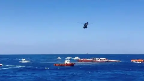 Reuters Several boats and a helicopter offer aid to a sinking a boat close to the Northern Cypriot port of Kyrenia.