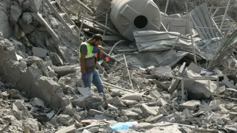 Getty Images An emergency worker looks through rubble in the aftermath of an airstrike on Ansar in Lebanon