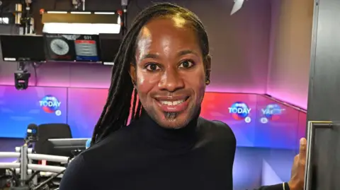 BBC Jason Arday smiling in the doorway of a BBC radio studio in December 2023