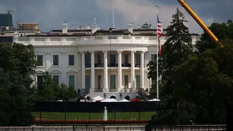Getty Images Exterior shot of the White House's South lawn, the Truman balcony (portico area enclosed by six white columns in the Ionic style, with a distinctive scroll-shaped ornaments called volutes on the capital. A yellow crane can be seen emerging from trees to the left of the frame